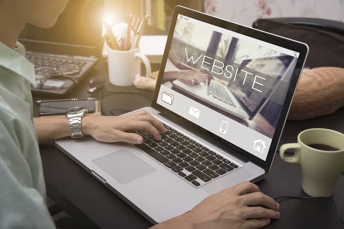 Person typing on a laptop showing a professional business website on screen